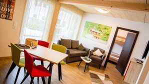 Un salon chaleureux comprenant un coin repas, un canapé, un téléviseur et un tableau accroché au mur.