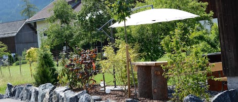 A residential area with a stone wall, a wooden bench, and a white umbrella.