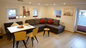 A modern living room with a sofa, dining table, chairs, and artwork on the walls. - Thanellerapart - Alpenapart Singer (Ehenbichl)