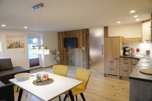 Une cuisine moderne avec des meubles en bois, un four encastré et un téléviseur à écran plat.