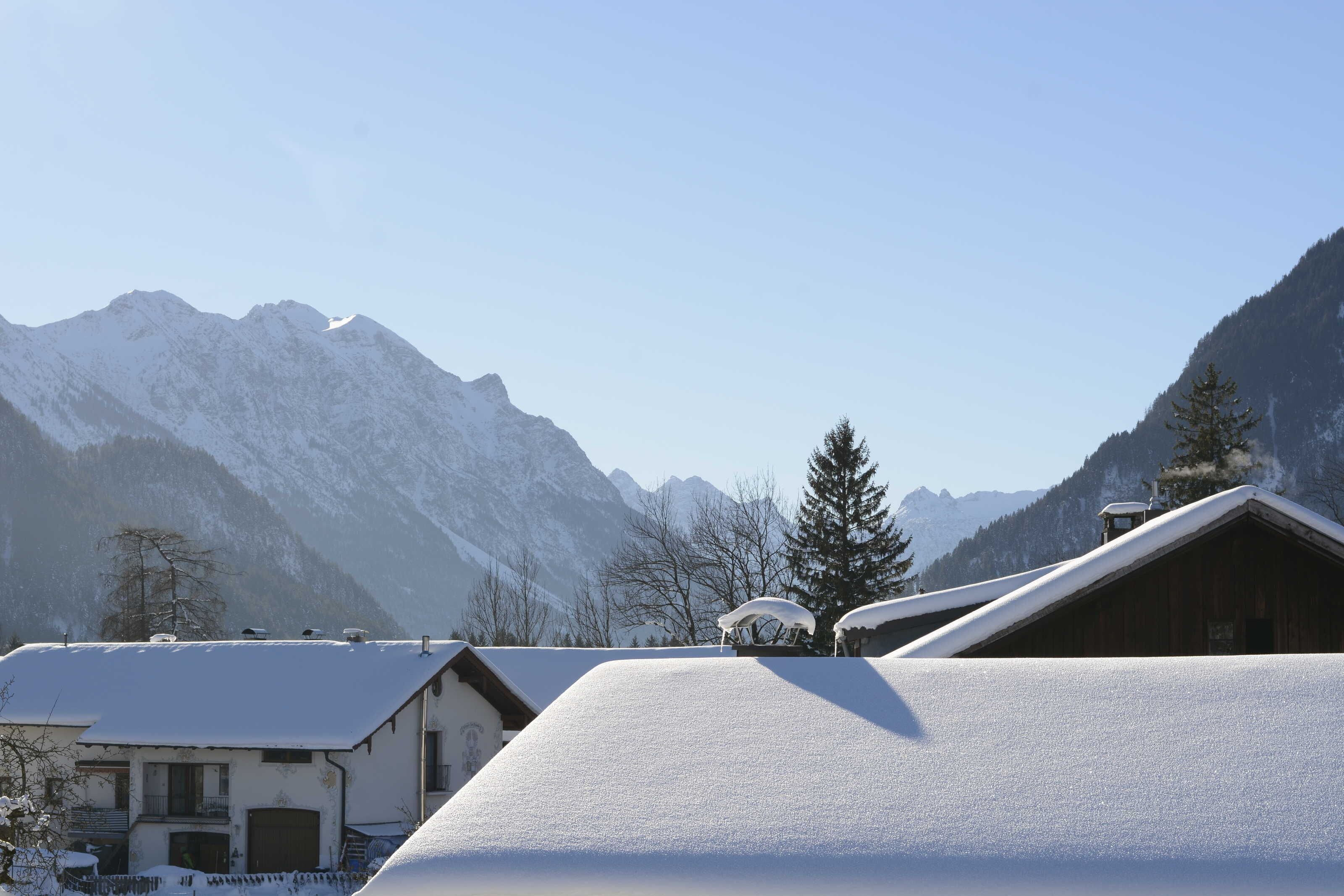 Un paysage montagneux enneigé, avec un bâtiment en bois au premier plan.