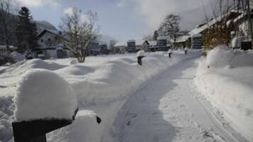 Eine verschneite Wohnstraße mit Häusern, blauem Himmel und einem mit Schnee bedeckten Briefkasten.