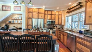 A kitchen with wooden cabinets, a central island, and a dining area with chairs. - 1/4 Acre Woods on Lake Waukewan! (Meredith)