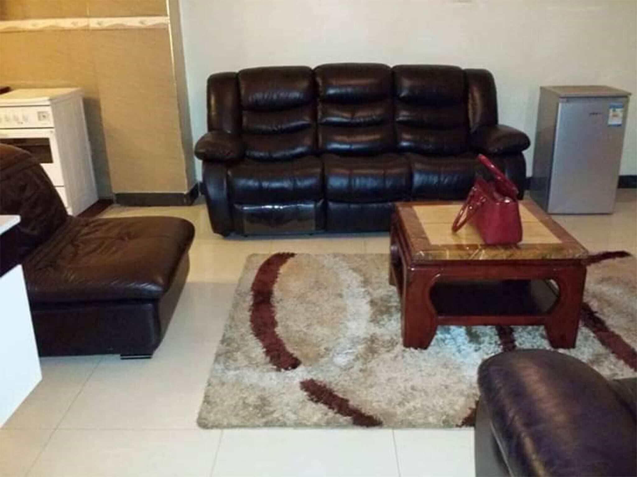 Una sala de estar con un sofá de cuero, una mesa de centro de madera y un bolso rojo encima.