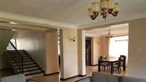 A spacious living room with a staircase, a dining area, and a chandelier. - A fully furnished apartment in the city of Kampala (Kampala)
