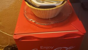En röd kylbox med Coca-Cola-logotyp, med en skål och ett par ätpinnar ovanpå.