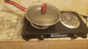 En portabel induktionshäll med en kastrull på, placerad på en yta med struktur.