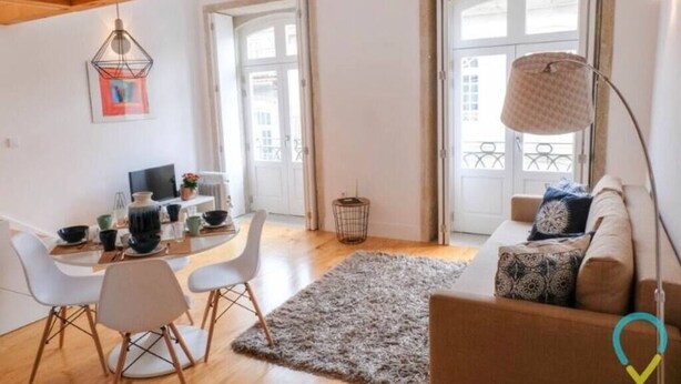 Un salon moderne avec un canapé, une table à manger et des chaises, ainsi qu’une grande fenêtre.