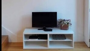 Une pièce avec un meuble de rangement blanc pour appareils multimédias, un téléviseur à écran plat et un tableau abstrait encadré accroché au mur.
