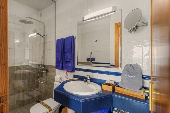 Un baño con cabina de ducha de vidrio, un lavabo, un espejo y un perchero para toallas.