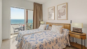 Et hotelværelse med en seng, et sengebord, en lampe, havudsigt og en loftsvifte.