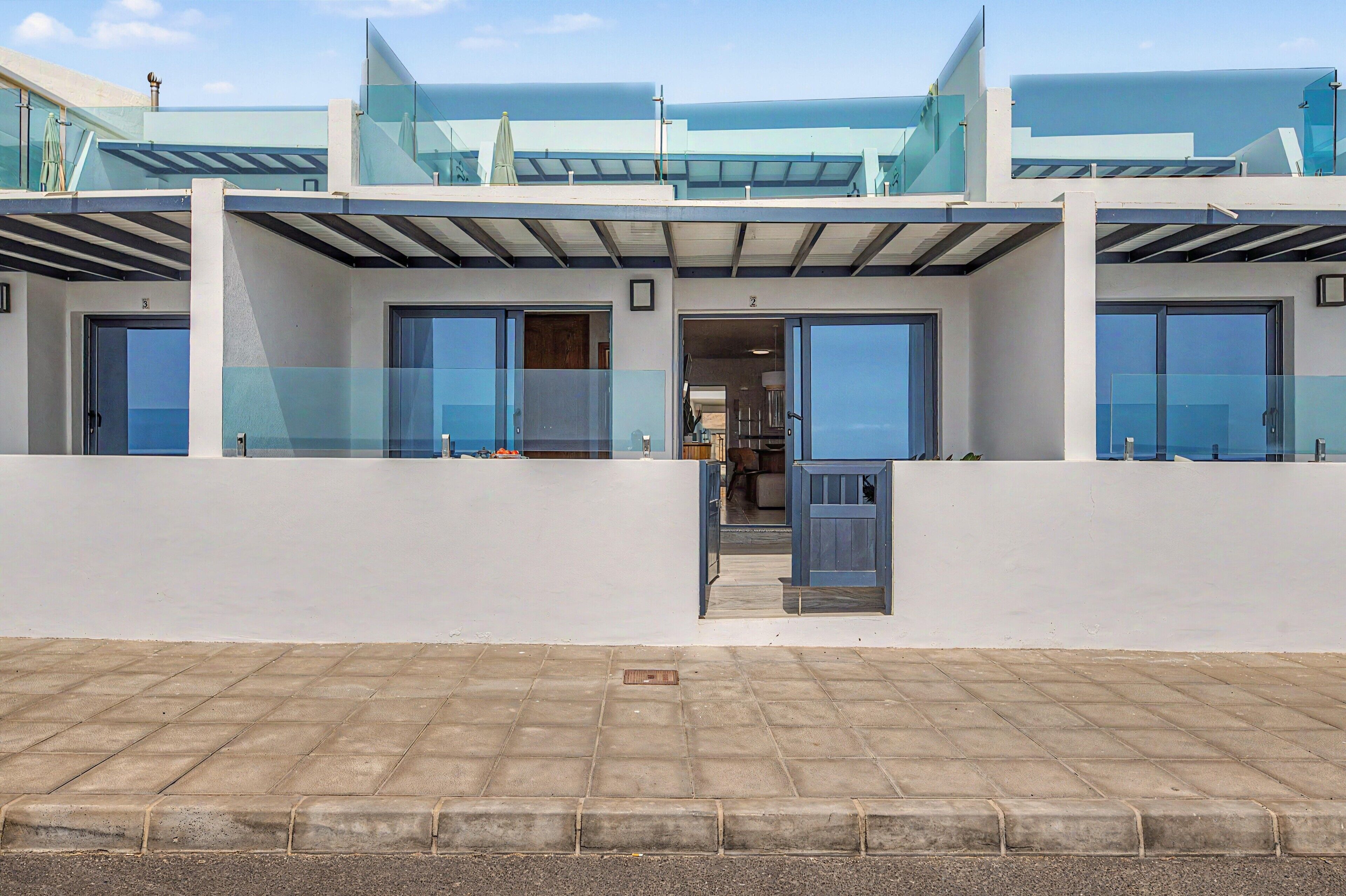 A modern building with a glass facade, a covered entrance, and a paved ground in front.