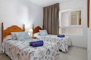 Een hotelkamer met twee bedden, een raam met gordijnen en een houten hoofdbord.