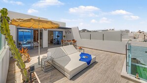 A rooftop terrace with a white sofa, a table, and an umbrella. - Holiday Apartment “Callao Beach 6” with Sea View, Terrace & Wi-Fi (Arrieta)