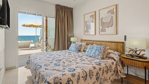 A bedroom with a bed, a nightstand, a TV, and a view of the ocean. - Holiday Apartment “Callao Beach 6” with Sea View, Terrace & Wi-Fi (Arrieta)