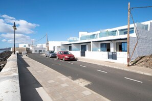 A modern building with a curved facade, a red car parked on the street, and a clear blue sky.