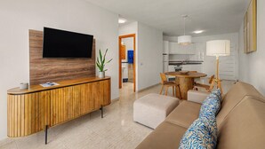 A modern living room with a wooden console, a flat-screen TV, a sofa, and a dining area with chairs and a table. - Holiday Apartment “Callao Beach 8” with Sea View, Terrace & Wi-Fi (Arrieta)