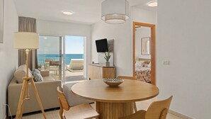 A modern room with a round wooden table, two chairs, a sofa, a TV, and a view of the sea through a sliding door. - Holiday Apartment “Callao Beach 8” with Sea View, Terrace & Wi-Fi (Arrieta)