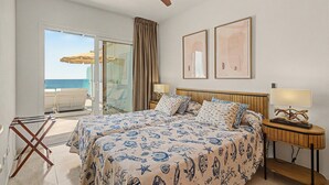 A hotel room with a bed, a ceiling fan, a view of the sea, and a balcony with a table and chairs. - Holiday Apartment “Callao Beach 8” with Sea View, Terrace & Wi-Fi (Arrieta)
