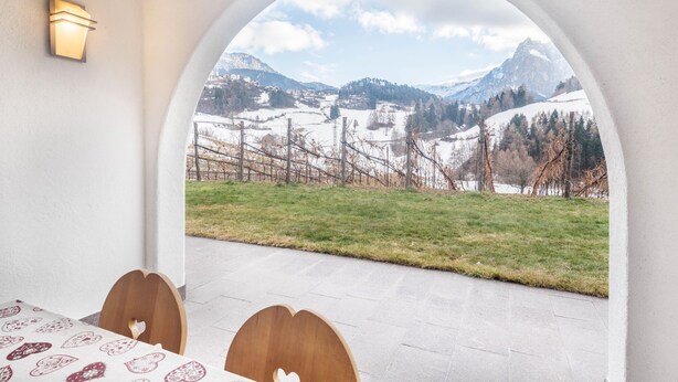Une pièce avec une fenêtre en arc offrant une vue dégagée, une table avec des chaises et un luminaire fixé au mur.