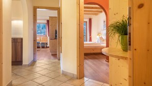 Passadís amb bigues de fusta, sòl de rajola i vista cap a una habitació amb llit i finestra.