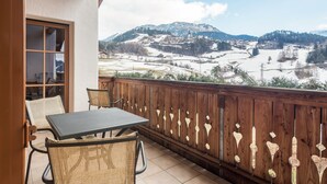 Un balcó amb taula i cadires, amb vista a un paisatge de muntanya.