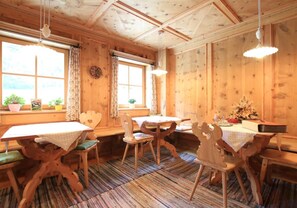 A wooden interior with a dining table, chairs, and a window with curtains. - Farm Vacations - "Fewo Molignon Paalhof" with Mountain View, Wi-Fi & Balcony (Kastelruth)