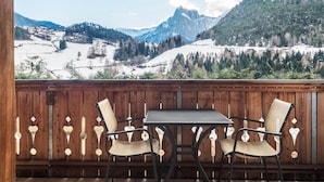 Un balcon doté d’une balustrade en bois, de deux fauteuils en osier et d’une table.