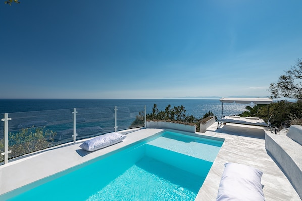 Un cielo azul despejado, una piscina y vistas al mar.