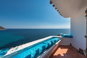 Un balcón con vista al mar, piso de baldosas y pared blanca.