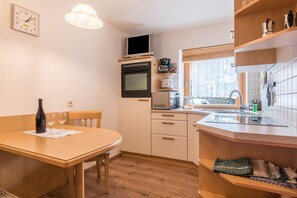 Une cuisine compacte équipée d’un four à micro-ondes, d’un four et d’une machine à café, un coin repas avec une table et des chaises, et une fenêtre donnant sur un paysage agréable.