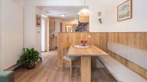A dining area with a wooden table, chairs, a bench, a hanging light fixture, and a potted plant. - Homely Apartment “Santner Villa Erna” with Mountain View (Seis)