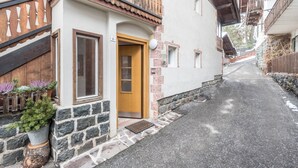 A narrow street with a building featuring a wooden door, stone steps, and potted plants. - Homely Apartment “Santner Villa Erna” with Mountain View (Seis)