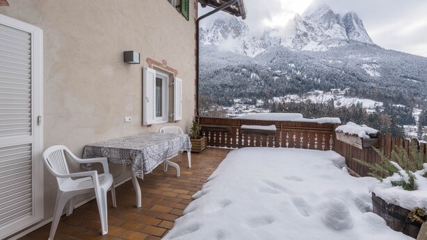 A patio with a table and chairs, a wooden fence, and a view of snow-covered mountains. - Homely Apartment “Santner Villa Erna” with Mountain View (Seis)