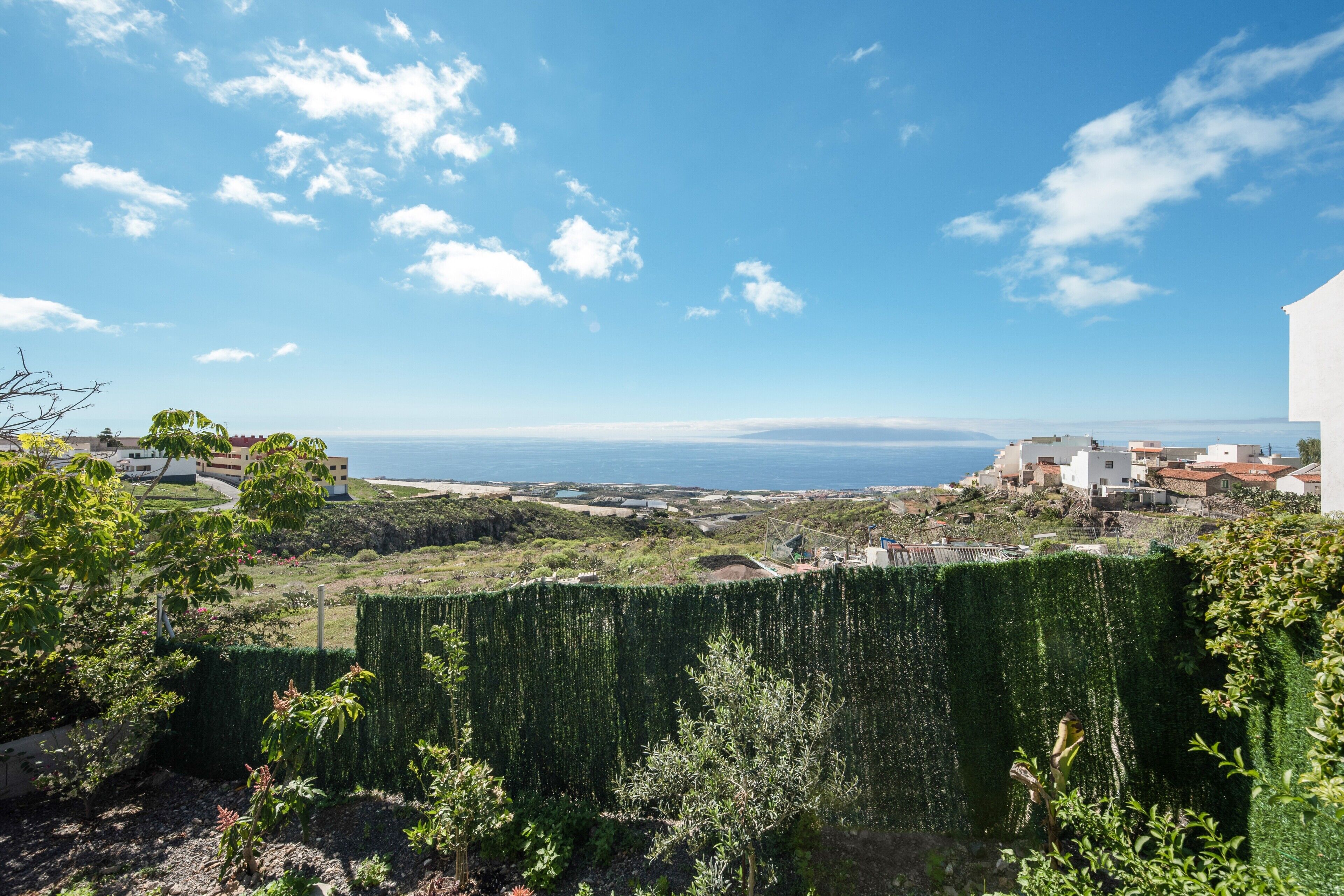 Une vue sur la côte, avec une haie, des bâtiments et un ciel dégagé.