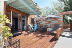 Une terrasse en bois avec des meubles d’extérieur, un mur en briques et un espace abrité.