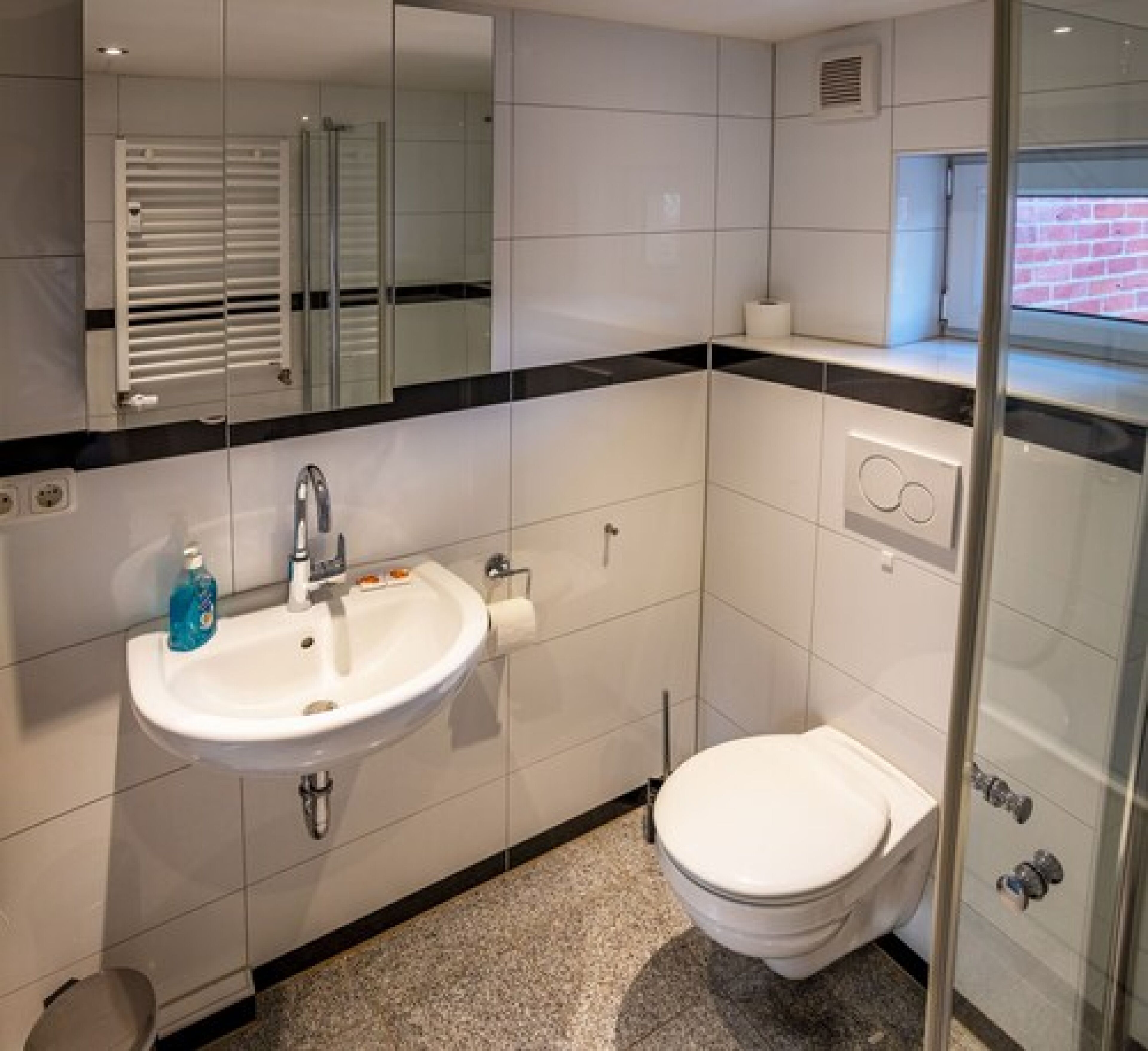 Ein modernes Badezimmer mit Waschbecken, Spiegel und Toilette in Weiß.