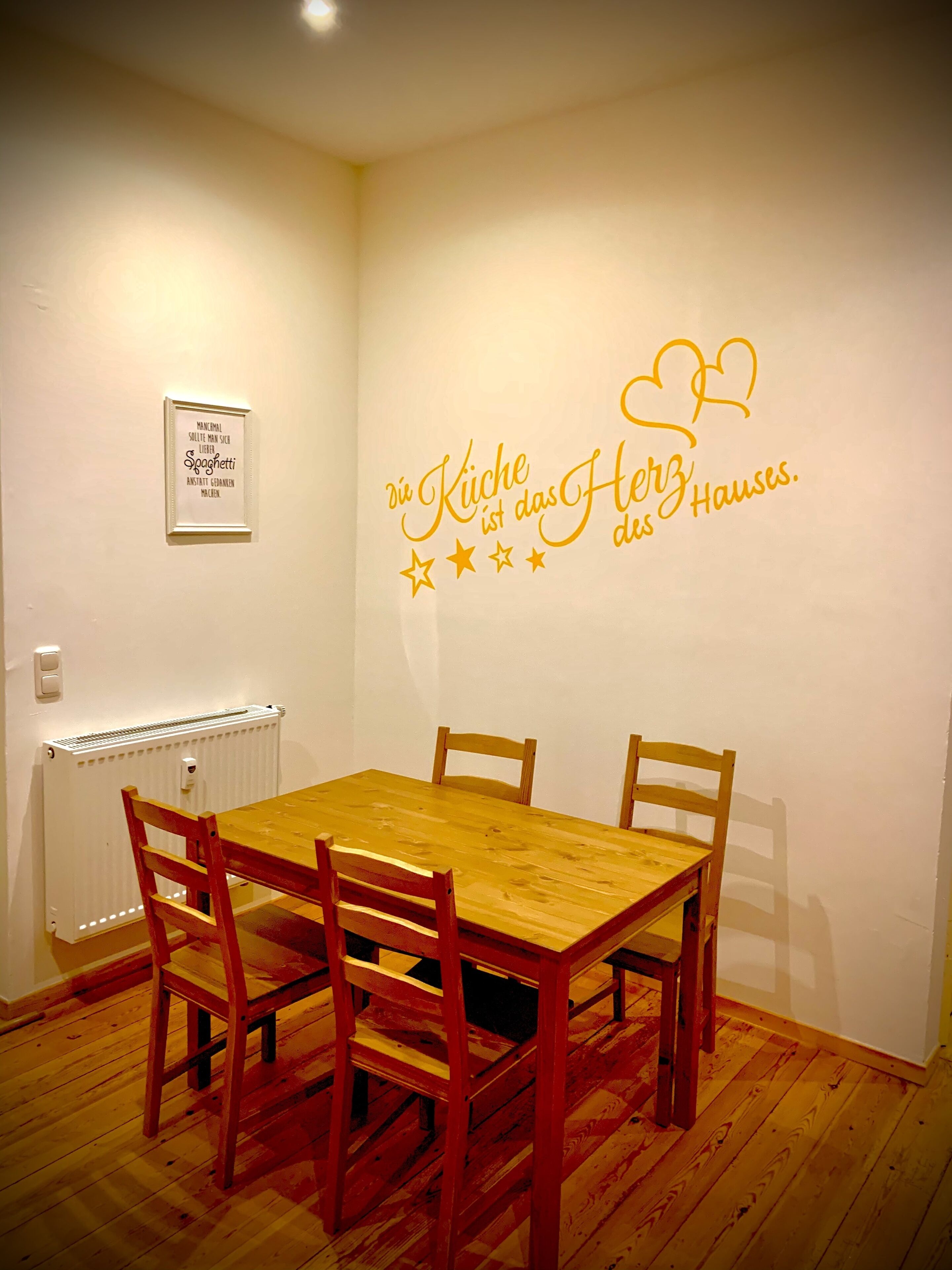 Ein Essbereich mit Holztisch und -stühlen, einem Heizkörper und einer Wand mit einem dekorativen Schild.