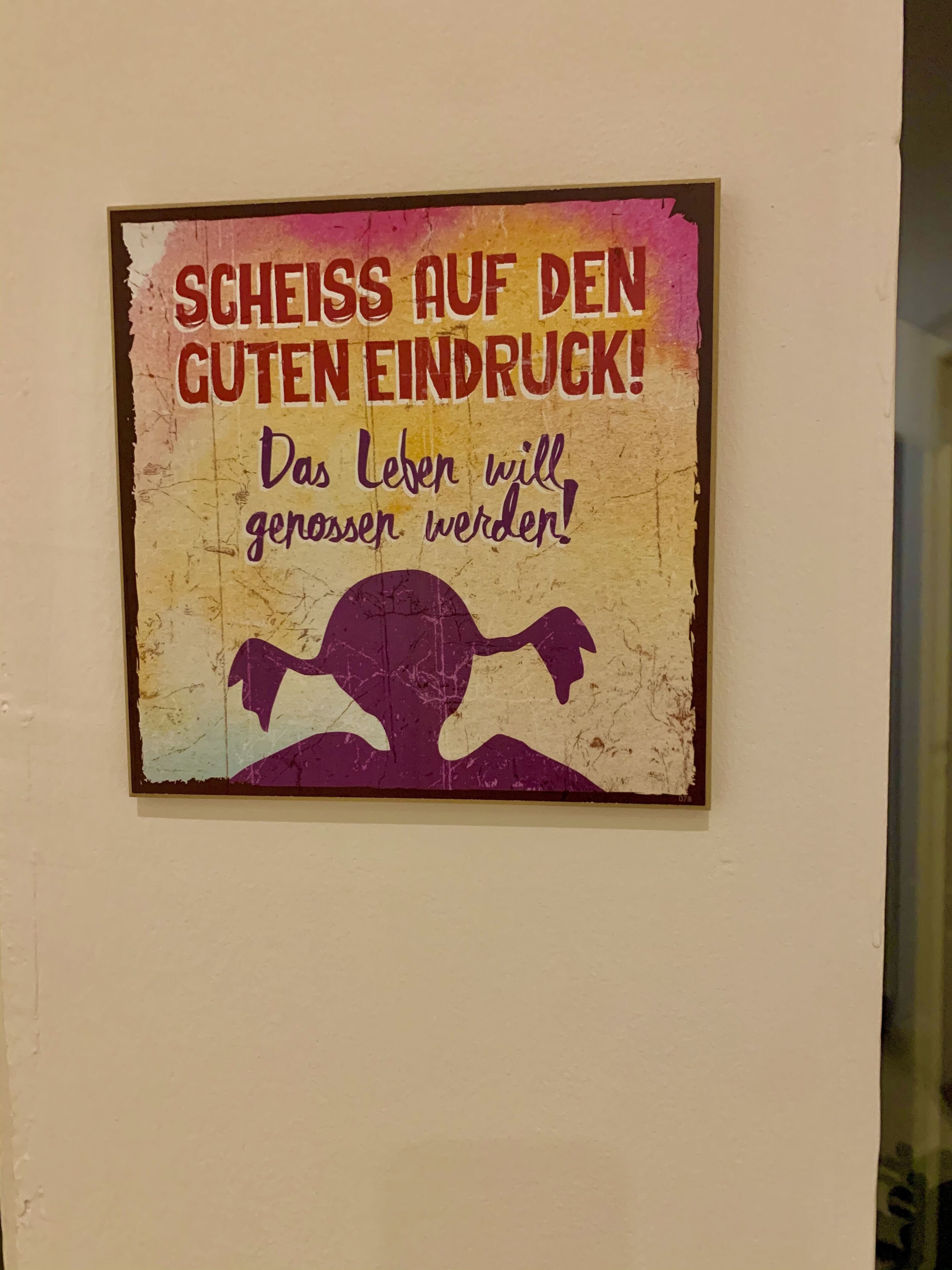 A wall with a poster that reads "SCEISS AUF DEN GUTEN EINDRUCK!" and "Das Leben will gerossen werden!" in German.