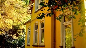 A yellow building with arched windows and a wooden door. - Seasides Villa Kunterbunt (Scharbeutz)