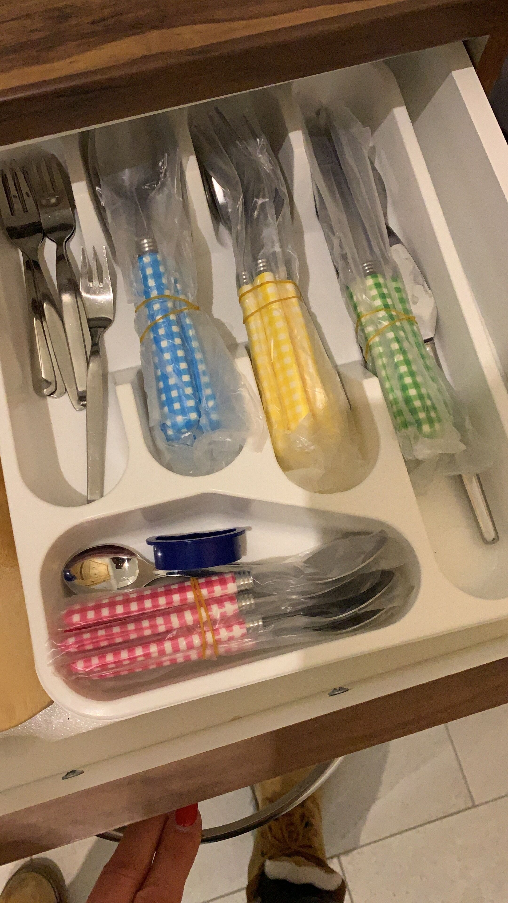 A drawer with neatly organized cutlery and napkins in various colors.