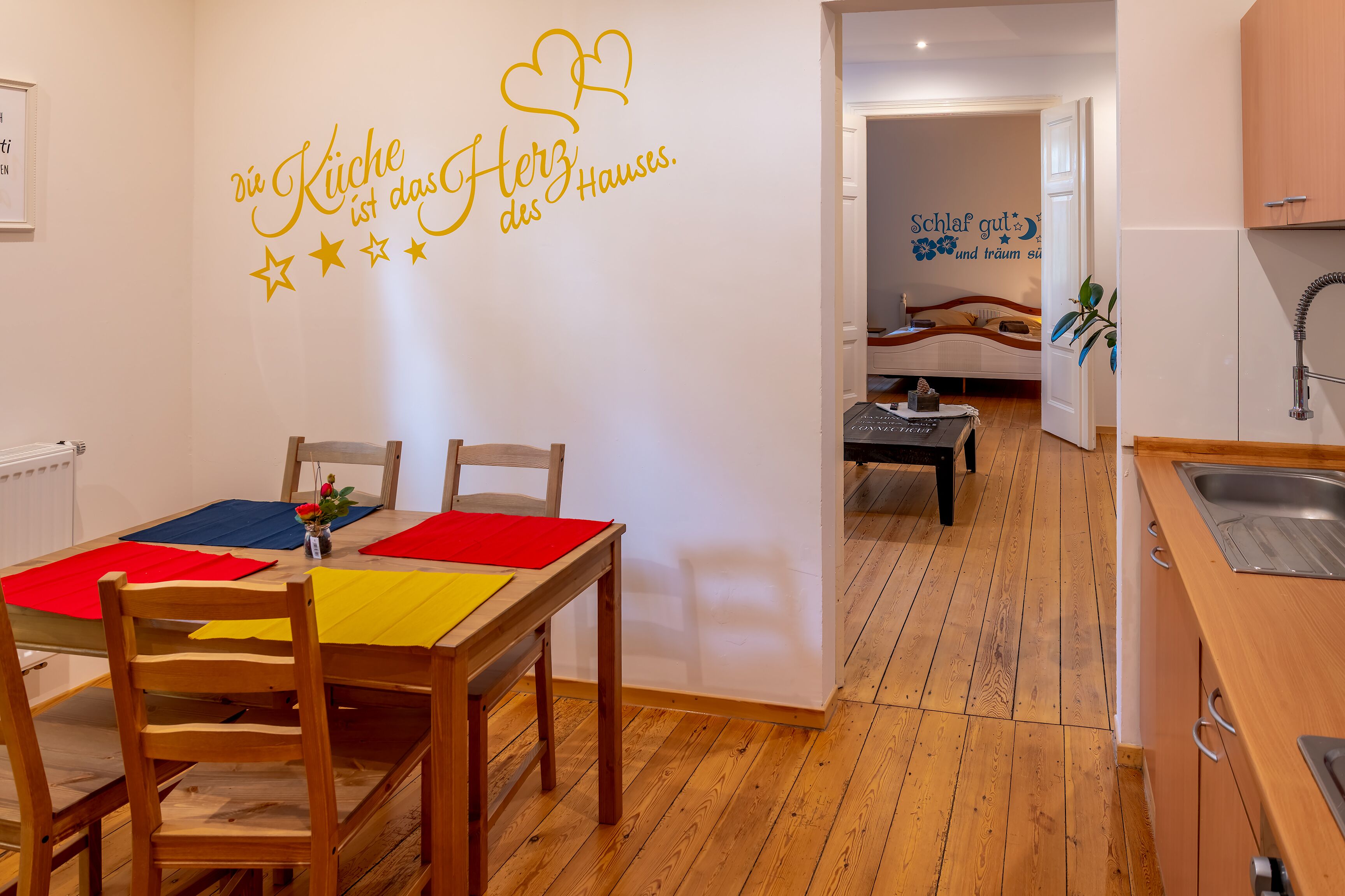 A cozy kitchen and dining area with wooden furniture and a wall decal.