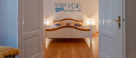 Un dormitorio con cama, mesitas de noche y un adorno en la pared.