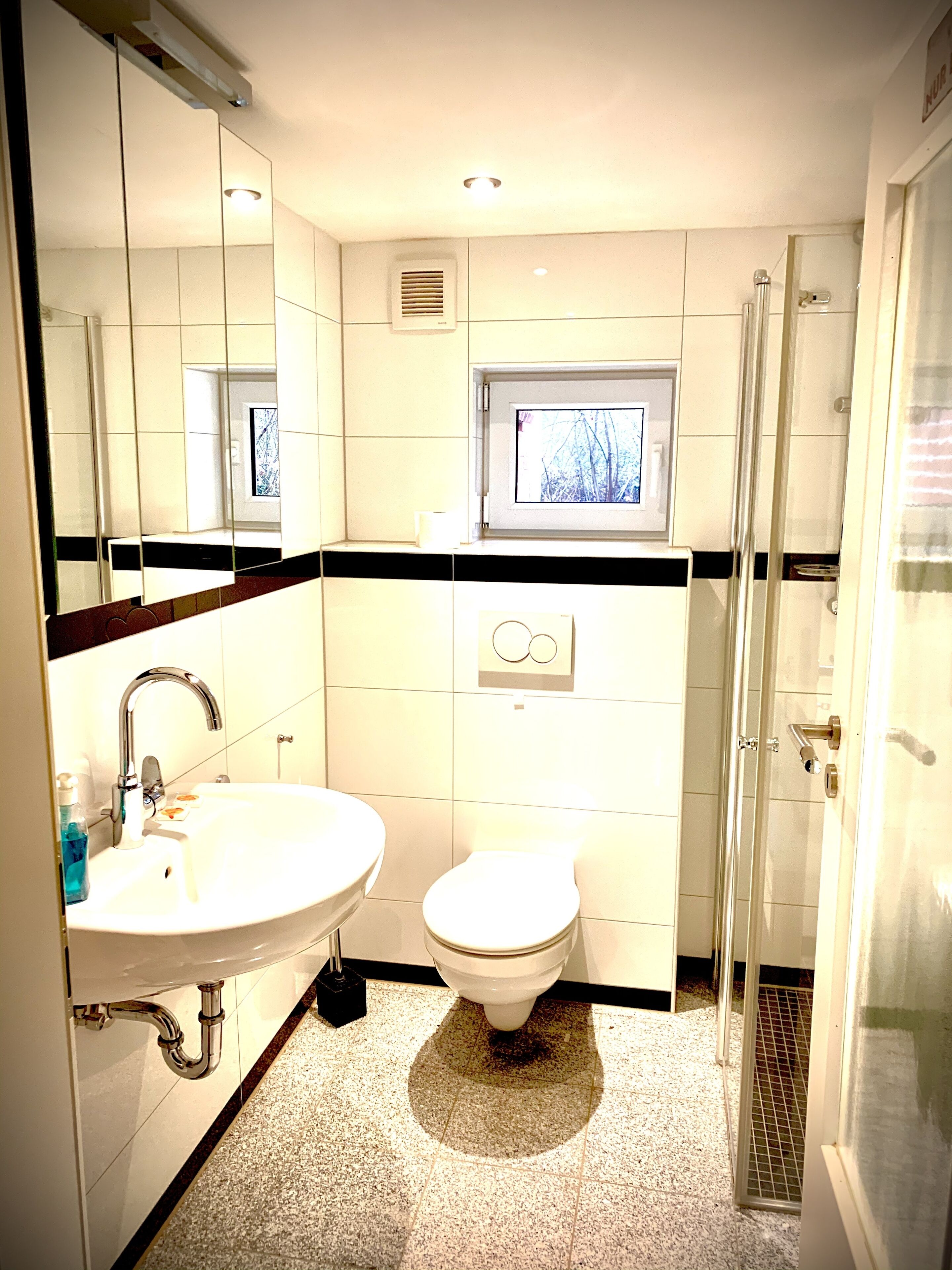 A bathroom with a sink, toilet, and a window above the toilet.