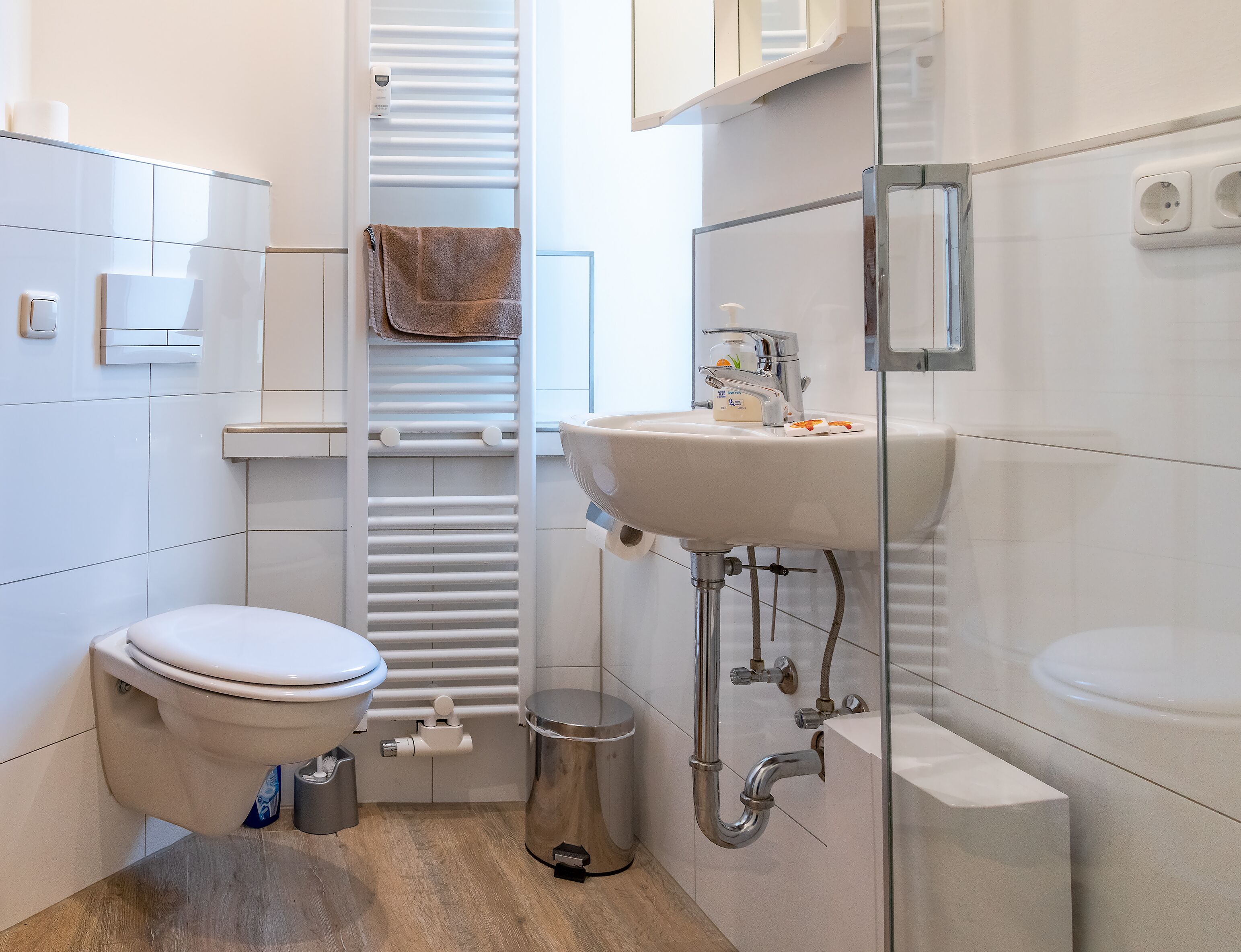 A small, modern bathroom with a toilet, sink, and towel rack.