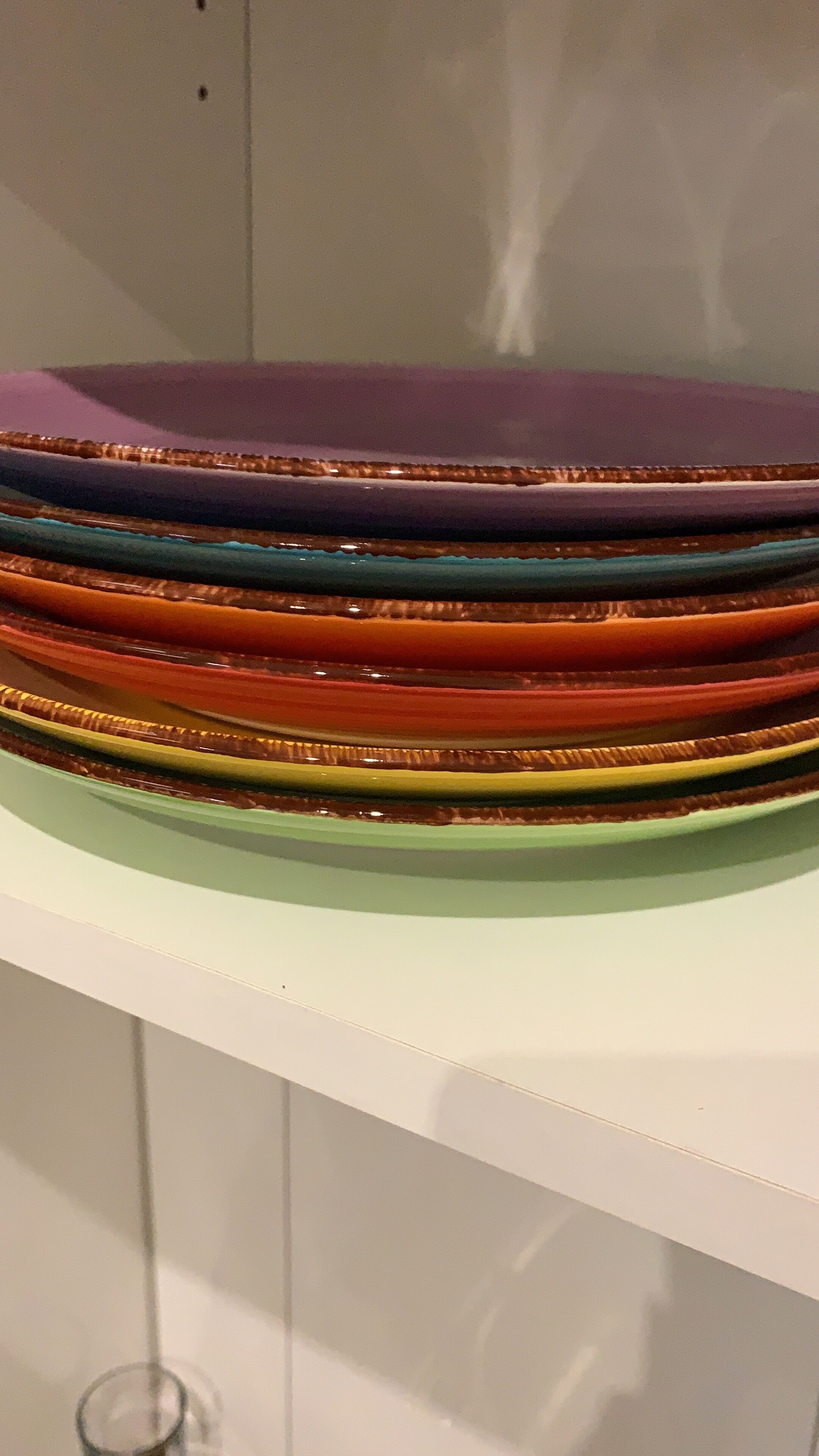 Una pila de platos coloridos sobre un estante blanco.