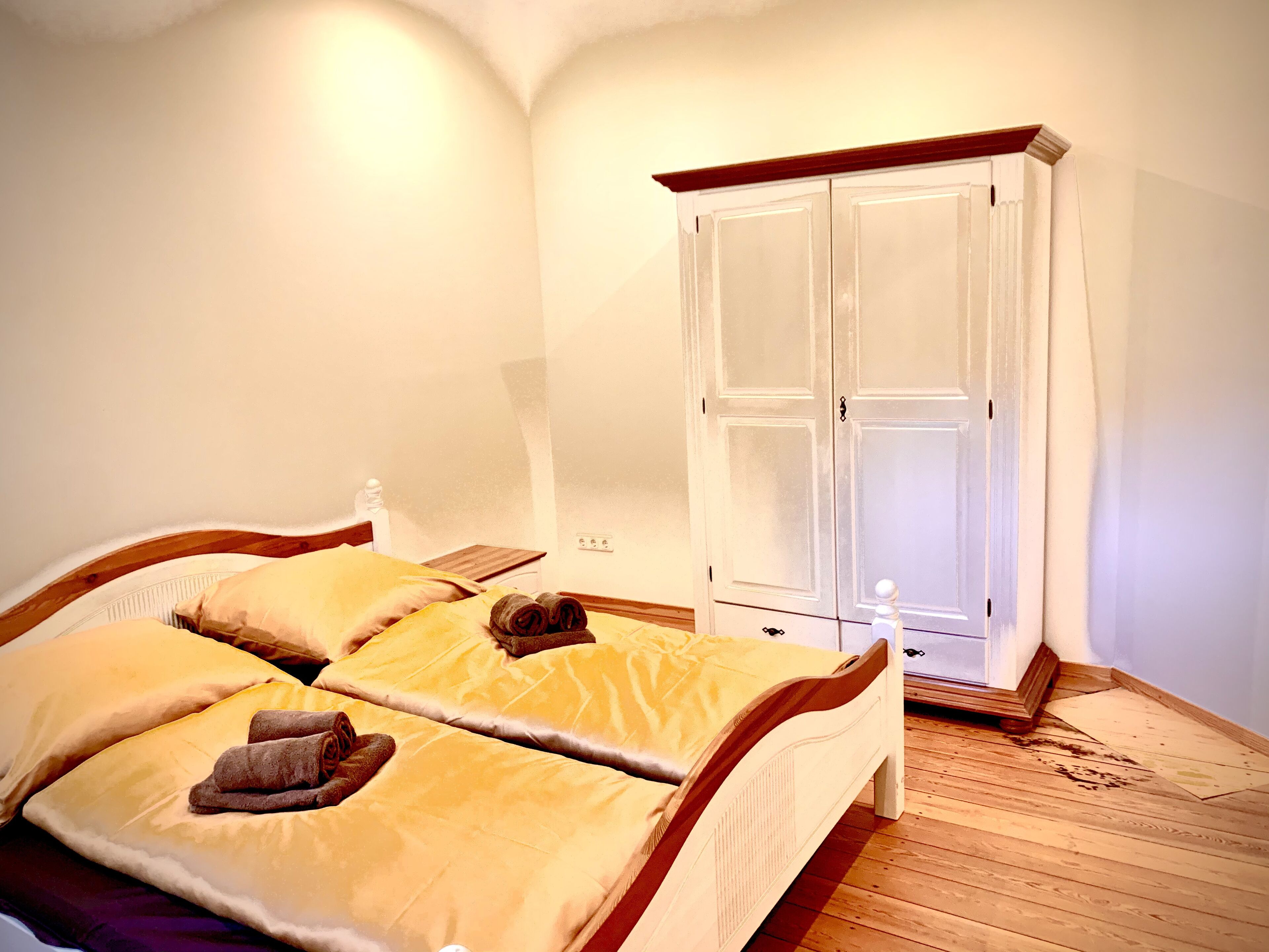 Une chambre avec deux lits, une armoire en bois et un plancher en bois.