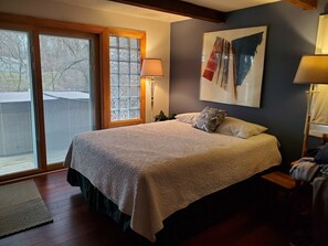 Ein Schlafzimmer mit einem großen Bett, einer Schiebetür, einem Bild an der Wand und einer Stehlampe.