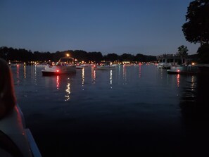 Ruhiges Wasserufer im Abenddämmerung mit Booten und einer angedockten Fähre.