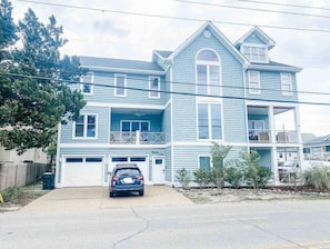 A two-story house with a garage, a balcony, and a car parked in front.